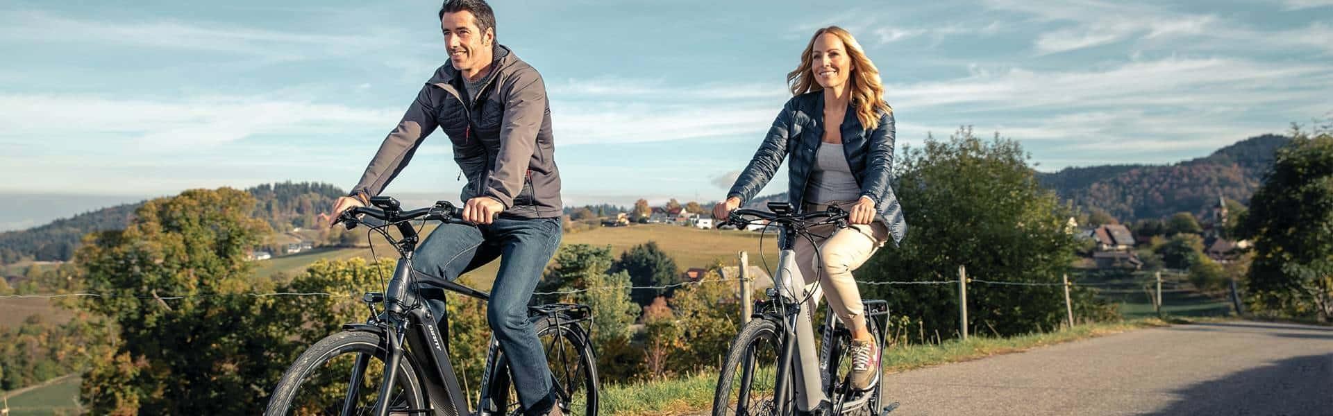 Paar macht mit ihren e-Bikes eine Fahrradtour durch die Natur.