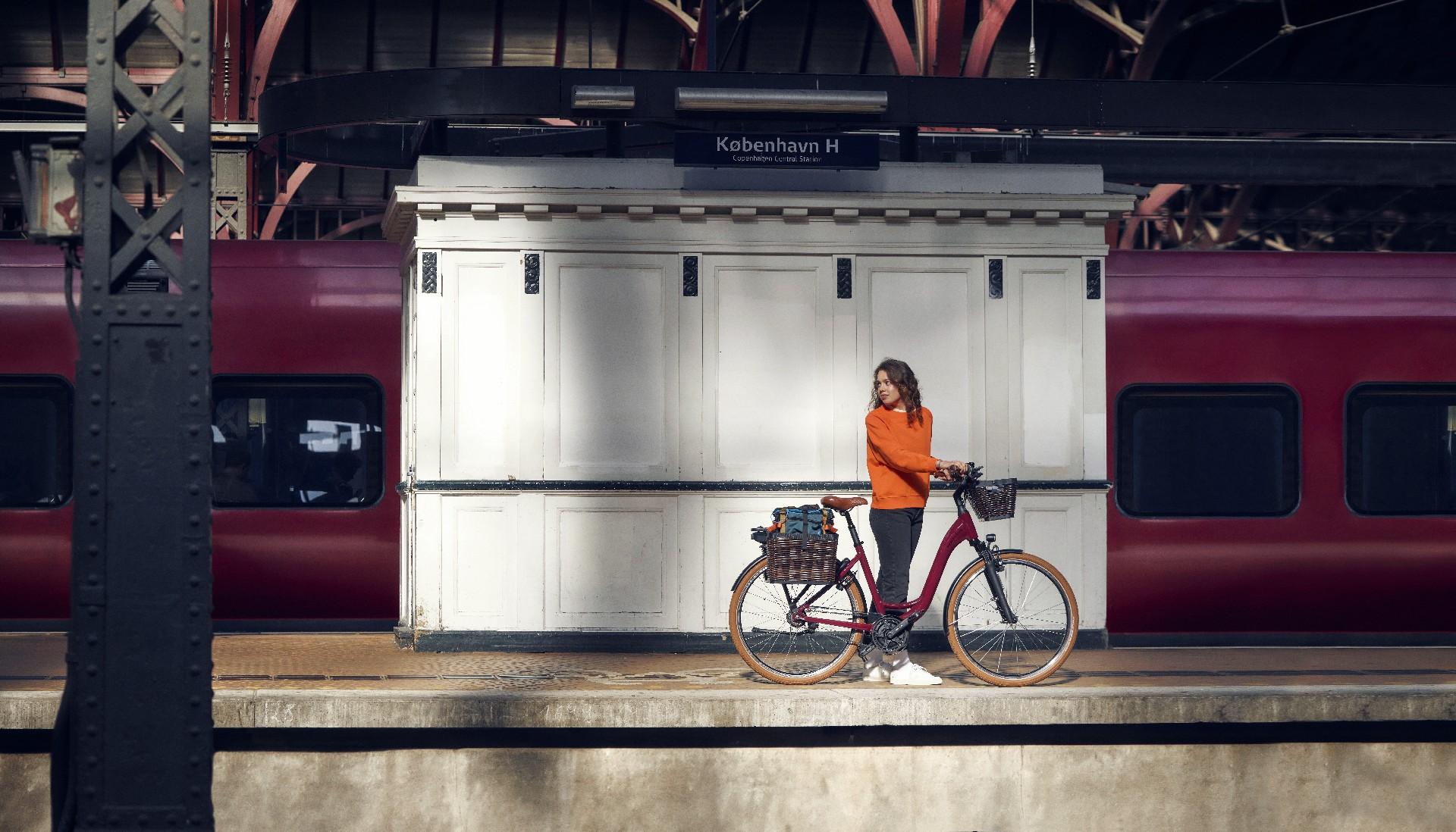 Eine Frau steht mit dem e-Bike Riese & Müller Swing am Bahnsteig
