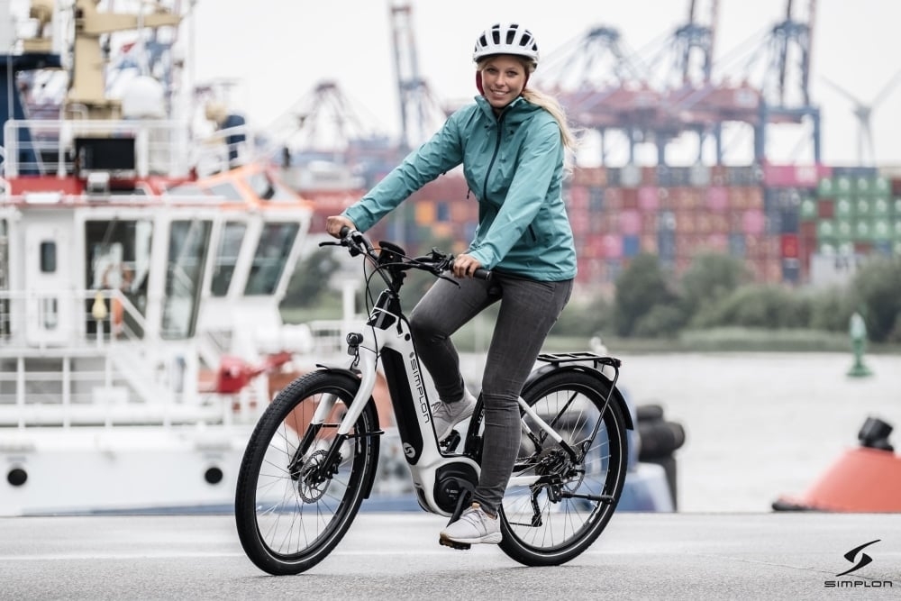 Frau auf Simplon Kagu Bosch Uni E-Bike vor Hafenhintergrund