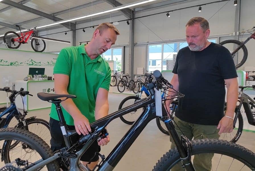 Zwei Männer betrachten ein schwarzes E-Bike in einem Fahrradgeschäft