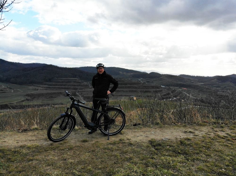 Person mit E-Bike vor hügeliger Landschaft
