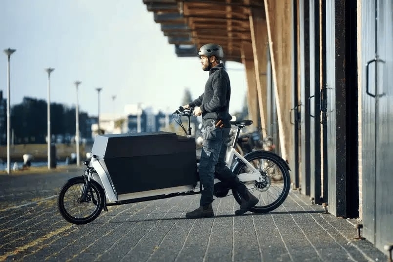 Mann mit Lasten-E-Bike vor moderner Architektur