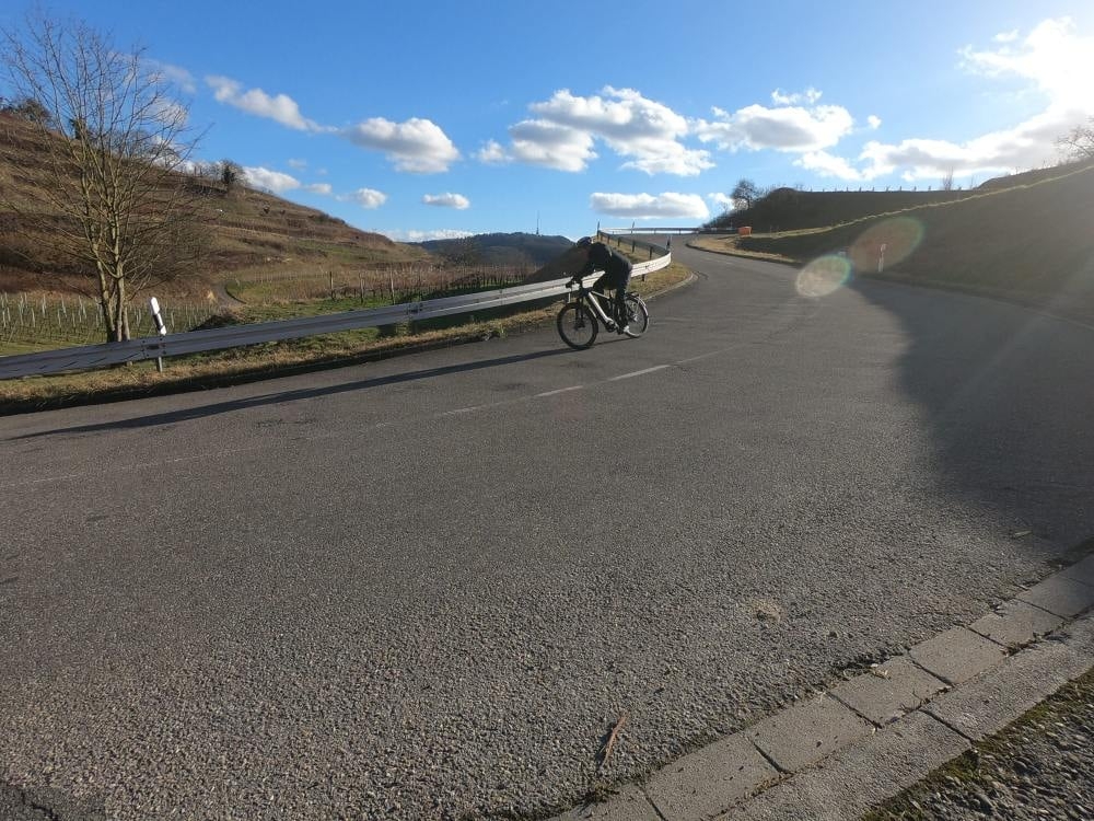 Radfahrer in Kurve auf sonniger Landstraße