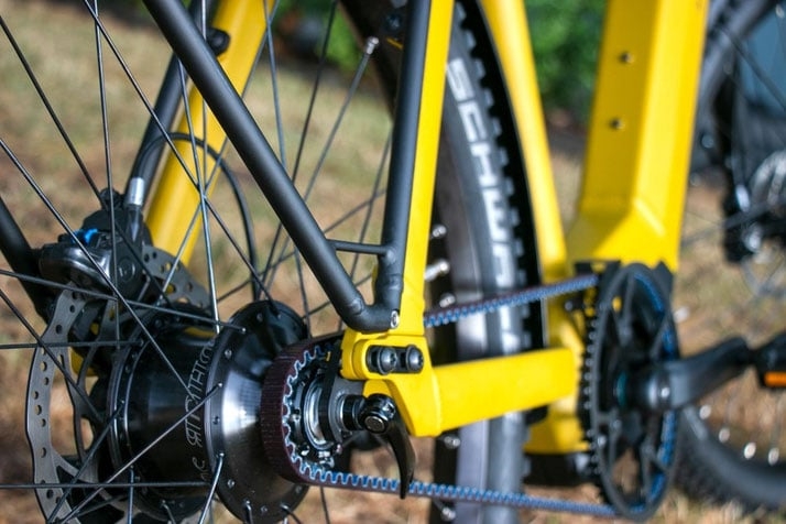 Nahaufnahme eines gelben Fahrrads mit Riemenantrieb und Scheibenbremse