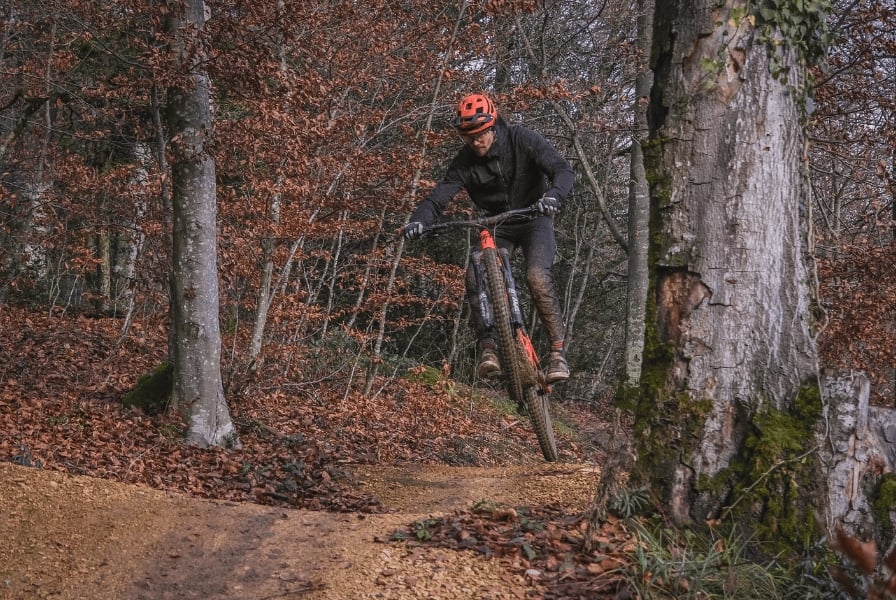 Mountainbiker springt im Herbstwald über eine Erhebung
