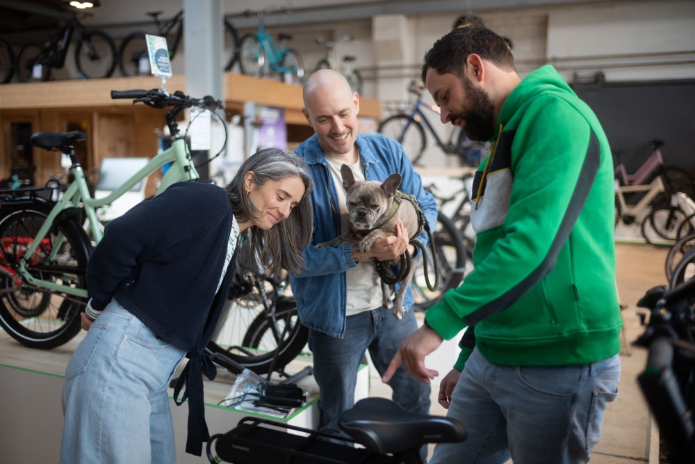 Drei Menschen begutachten ein Lastenrad in einem Fahrradladen. Perfekt für umweltbewusste und praktische Mobilität