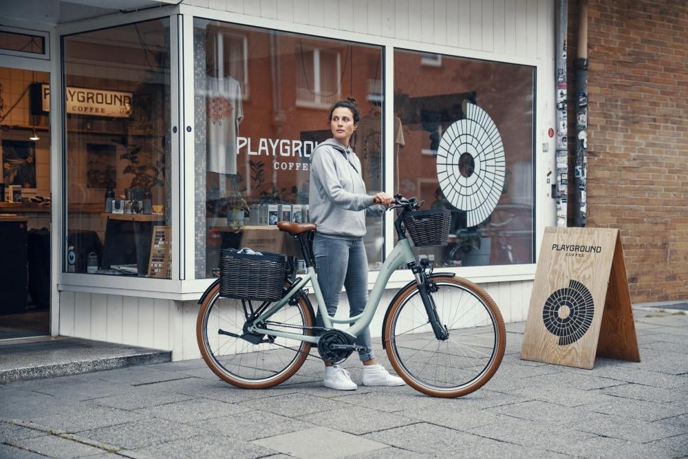 Frau mit E-Bike vor einem Café in urbaner Umgebung