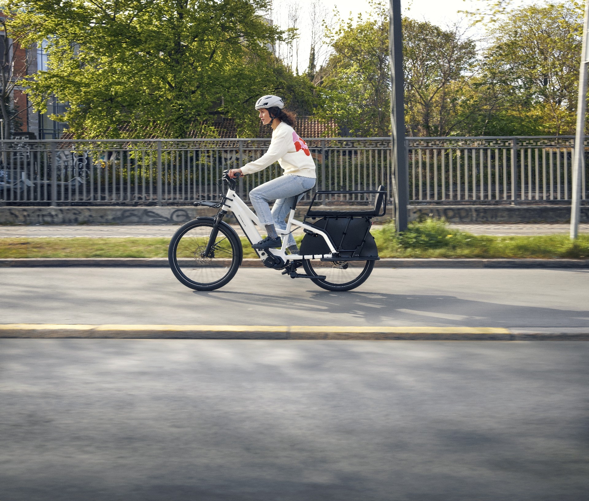 Eine Frau sitzt auf einem Multicharger Lastenrad von Riese und Müller