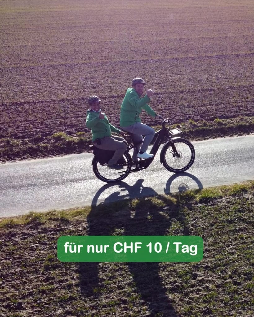 Zwei Personen auf E-Bike auf ländlicher Straße mit Werbetext