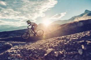 Mountainbiker bei Sonnenuntergang auf steiniger Strecke