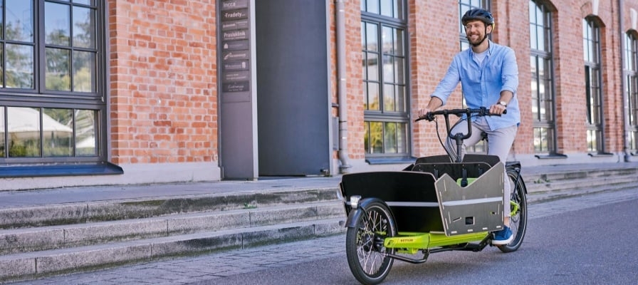 Mann fährt Cargoline FS 800 Lastenrad vor Backsteingebäude