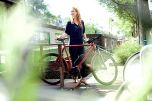 Frau mit rotem Fahrrad im Freien bei sonnigem Wetter