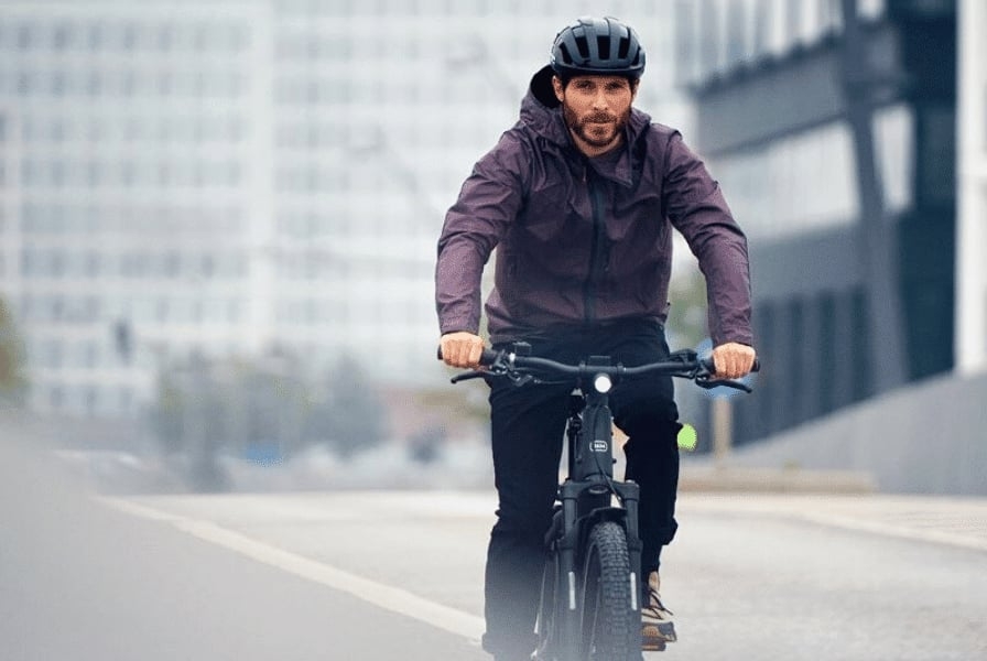Mann fährt E-Bike auf städtischer Straße mit Helm